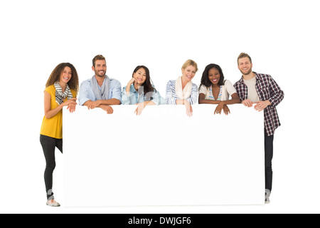 Lächelnde Gruppe junger Freunde stützte sich auf großes poster Stockfoto