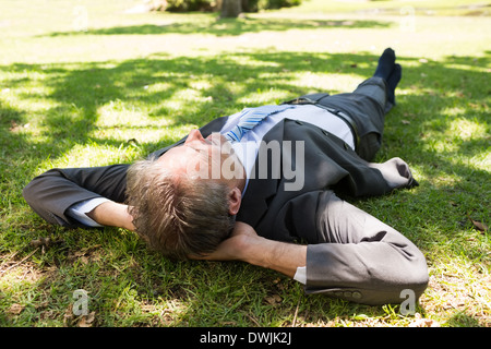 Geschäftsmann, liegend auf dem Rasen im park Stockfoto