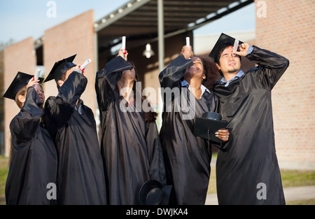 Studenten im Abschluss Kleid Blick durch Zertifikate auf Lager Stockfoto