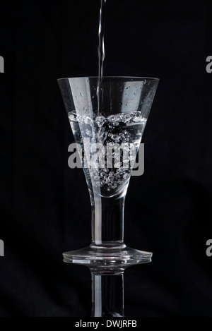 Wasser in ein Glas gegossen wird Stockfoto