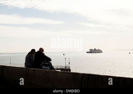 Paar sitzen am Deich in Old Portsmouth beobachten die Fähre kommen. Stockfoto