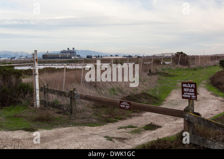 Wildlife Refuge und halten Sie Zeichen im Vordergrund und eine erdgasbefeuerte Kraftwerk hinter einem Zaun im Hintergrund. Stockfoto