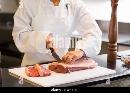 Mittleren Bereich der Hände, schneiden Fleisch in Küche Stockfoto
