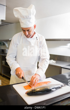 Konzentriert männlichen Chef schneiden Fisch in Küche Stockfoto