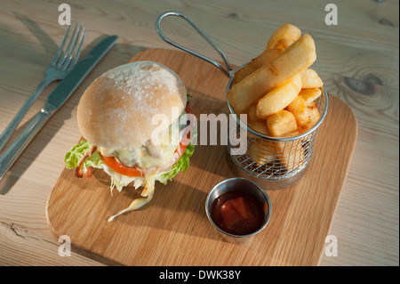 Beefburger mit Käse und Speck mit ein Ohrenschmaus gesäumt oder gebratene Kartoffeln und eine kleine Portion Tomaten-Ketchup. Stockfoto