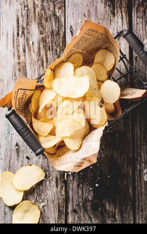 Draufsicht auf Korb mit Kartoffel-Chips mit Meersalz über alten Holztisch. Stockfoto