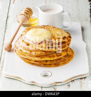 Stapel von kleinen Pfannkuchen mit Butter und Honig Stockfoto