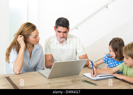 Eltern, die mit Laptop während Kinder Färbung Stockfoto