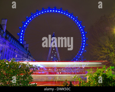 Das London Eye in der Nacht mit unscharfen London red Bus vorbei im Vordergrund South Bank London, England UK Stockfoto