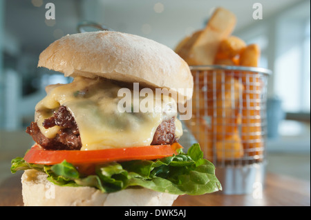 Beefburger mit einer Beilage von Pommes frites oder abgebrochenen Kartoffeln, mit einem Salat mit geschmolzenem Käse und Speck als Statist zu füllen. Stockfoto