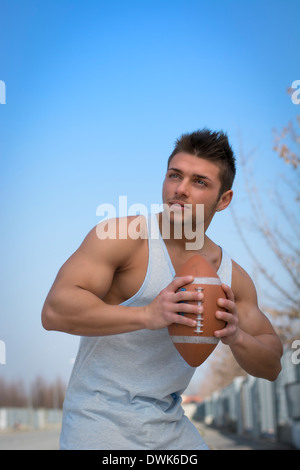 Muskuläre american Footballspieler bereit, den Ball in der hand zu werfen. Im Freien Schuss Stockfoto