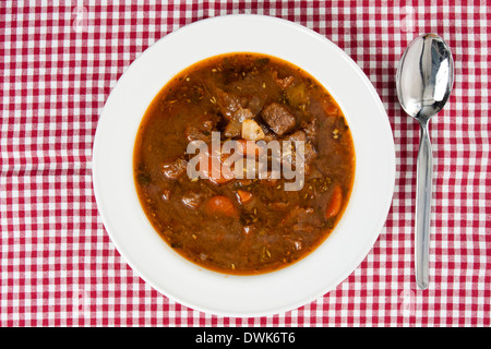 Gulaschsuppe in Schüssel auf karierten Tischdecke weiß Stockfoto