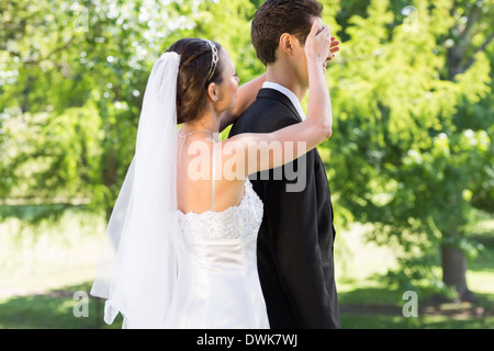 Junge Braut für Augen des Bräutigams im Garten Stockfoto