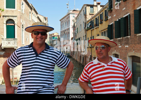 Nahaufnahme von Gondolieri auf Kanalbrücke mit rot und blau gestreiften Oberteilen, Venedig, Veneto, Italien, Europa Stockfoto