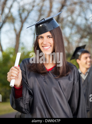 Frau In Graduation Kleid College Campus Diplom festhalten Stockfoto