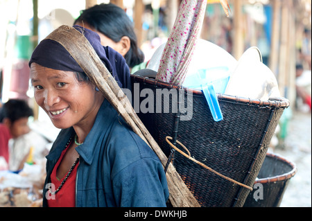 Lächelnd Naga Frau tragen traditionelle gewebte Zuckerrohr Kopf Korb, Einkaufen in Tizit Dorf Wochenmarkt, Nagaland, Indien Stockfoto