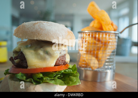 Beefburger mit einer Beilage von Pommes frites oder abgebrochenen Kartoffeln, mit einem Salat mit geschmolzenem Käse und Speck als Statist zu füllen. Stockfoto