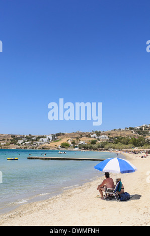 Ein paar sitzt unter einem Sonnenschirm auf der Insel Paros Livadia Beach, Parikia, Griechenland Stockfoto