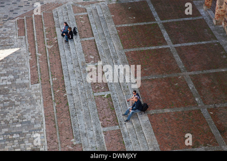 Menschen sitzen auf den Stufen der Kathedrale (Duomo) auf der Piazza Grande, Montepulciano, Toskana, Italien. Stockfoto