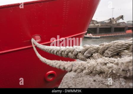 starke Festmacher Seil als ein Holdfast, leuchtend rote Stahl Bootsrumpf auf Gezeiten Steg Wharf am Fluss Themse zu schützen Stockfoto