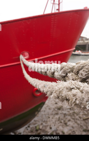 starke Festmacher Seil als ein Holdfast, leuchtend rote Stahl Bootsrumpf auf Gezeiten Steg Wharf am Fluss Themse zu schützen Stockfoto