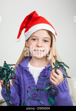 Mädchen In Nikolausmütze mit Lichterketten Stockfoto