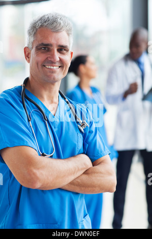 fröhliche mittleren Alter Arzt mit verschränkten in Klinik Stockfoto