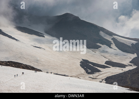 Touristen, die über ein Schneefeld, Mutnovsky Vulkan, Kamtschatka, Russland, Eurasien Stockfoto