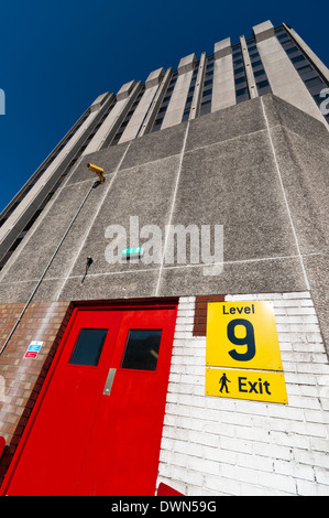Einem hoch aufragenden Büro Betonblock mit Eingang vom Parkplatz auf Ebene 9 mit starker Sonneneinstrahlung und dunkelblauen Himmel Stockfoto