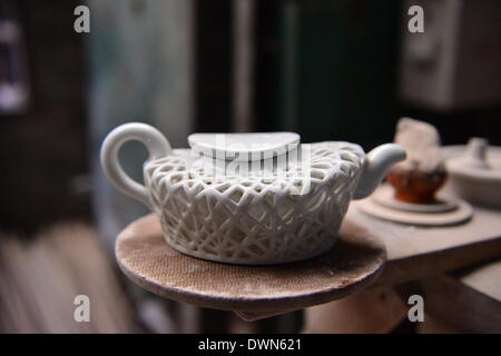 Jingdezhen. 11. März 2014. Foto aufgenommen am 11. März 2014 zeigt eine Teekanne von Porzellan Handwerker Zhang Maosheng für die Olympischen Spiele 2008 in Zhangs Studio in Jingdezhen, Osten Chinas Jiangxi Provinz gemacht. Zhang wurde Porzellan Werke basierend auf einer Reihe von Wahrzeichen Architekturen und wichtige Ereignisse in China gefertigt. Sein Atelier befindet sich in einer kleinen Gasse in Jingdezhen, bekannt für seine Tradition der Porzellan-Herstellung als Chinas "Porzellan-Hauptstadt". © Zhou Mi/Xinhua/Alamy Live-Nachrichten Stockfoto