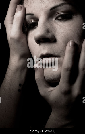 Ein Schuss launisch Gesicht eines Mannes mit Händen berührt sein Gesicht, eine geheimnisvolle kreative Porträt-Konzept Stockfoto