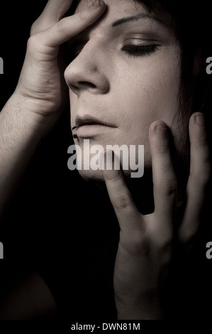 Ein Schuss launisch Gesicht eines Mannes mit Augen geschlossen und Hände berühren sein Gesicht, eine geheimnisvolle kreative Porträt-Konzept Stockfoto