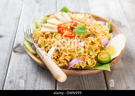 Würzig gebratene Curry-instant-Nudeln oder malaysischen Stil Maggi Goreng Mamak. Asiatische Küche, Esstisch aus Holz Einstellung servierfertig. Frisch heiß mit gedünstetem Rauch. Stockfoto