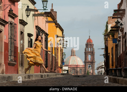 Junge Frau tanzt auf gepflasterten Straße (Recreo), San Miguel de Allende, Guanajuato, Mexiko, Nordamerika Stockfoto