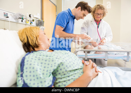 Arzt untersuchen Neugeborenes während Eltern sah sie Stockfoto
