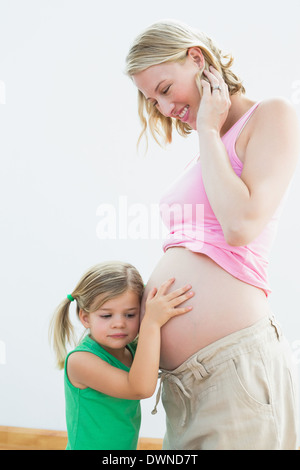 Kleines Mädchen hören Blonde Mütter schwangeren Bauch Stockfoto