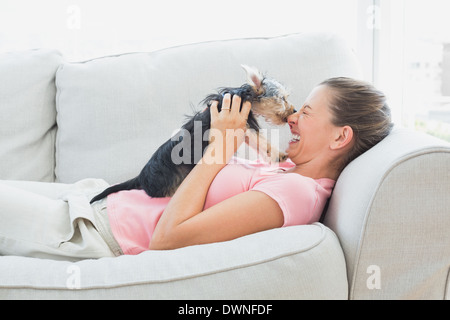 Glückliche Frau spielt mit ihrem Yorkshire-Terrier auf der couch Stockfoto