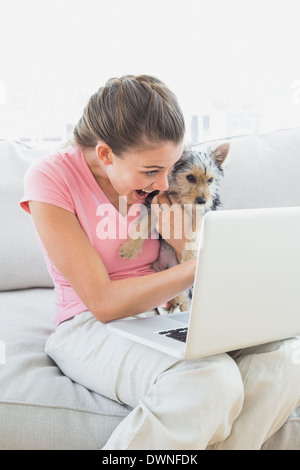Glückliche Frau hält ihr Yorkshire Terrier auf der Couch mit laptop Stockfoto