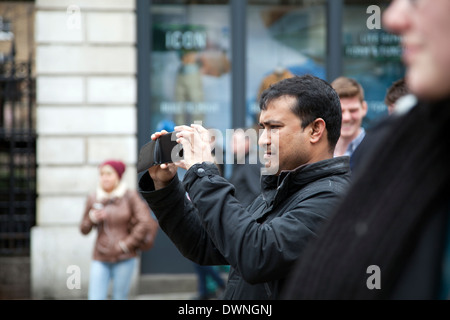 Mann mit mobilen Gerät fotografieren Darsteller am Covent Garden Market Stockfoto