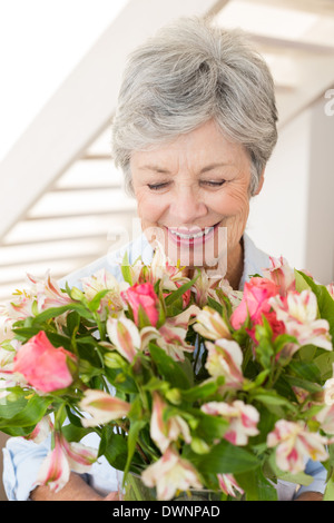 Pensionierte Frau Blumenstrauß hält lächelnd Stockfoto