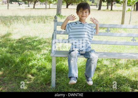 Glückliche Junge sitzt auf der Bank im park Stockfoto