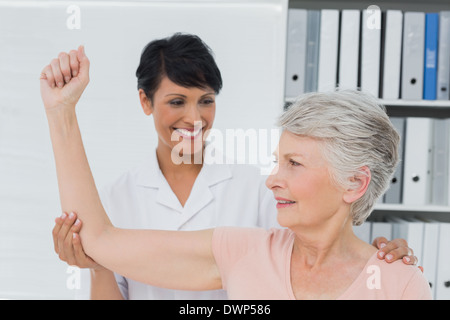 Unterstützung der älteren Frau, die ihre Hand ausstrecken, Physiotherapeut Stockfoto