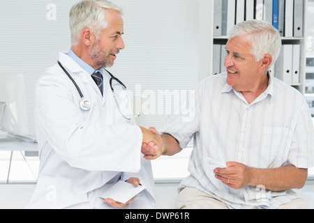 Lächelnde ältere Patient und Arzt Händeschütteln Stockfoto