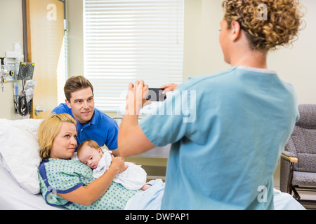 Krankenschwester fotografieren paar mit Neugeborenen durch Handy Stockfoto