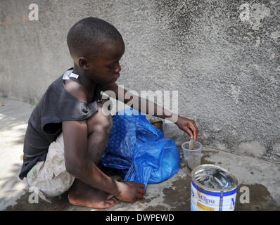 Maputo, Mosambik. 27. Februar 2013. Ein Kind reinigt er in einem Abwasserkanal in Bairro von Maputo, Mosambik, 27. Februar 2013 gefangenen Fische. Foto: Britta Pedersen - kein Draht-SERVICE-/ Dpa/Alamy Live News Stockfoto