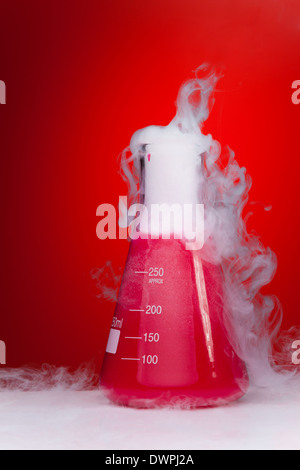 Chemie-Experiment-Kolben mit Rauch auf rotem Grund Stockfoto