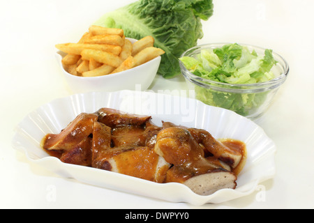 eine Currywurst mit Pommes Frites und Salat Stockfoto