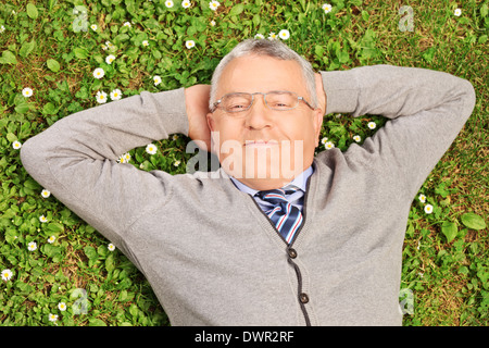 Reifer Mann liegend auf dem grünen Rasen in einem Feld Stockfoto