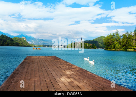 Hölzerne Pier am Bleder See in Slowenien mit der berühmten Insel und Schloss im Hintergrund Stockfoto