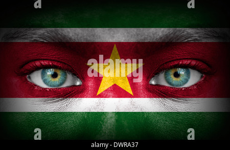 Menschliches Gesicht gemalt mit Flagge von Suriname Stockfoto